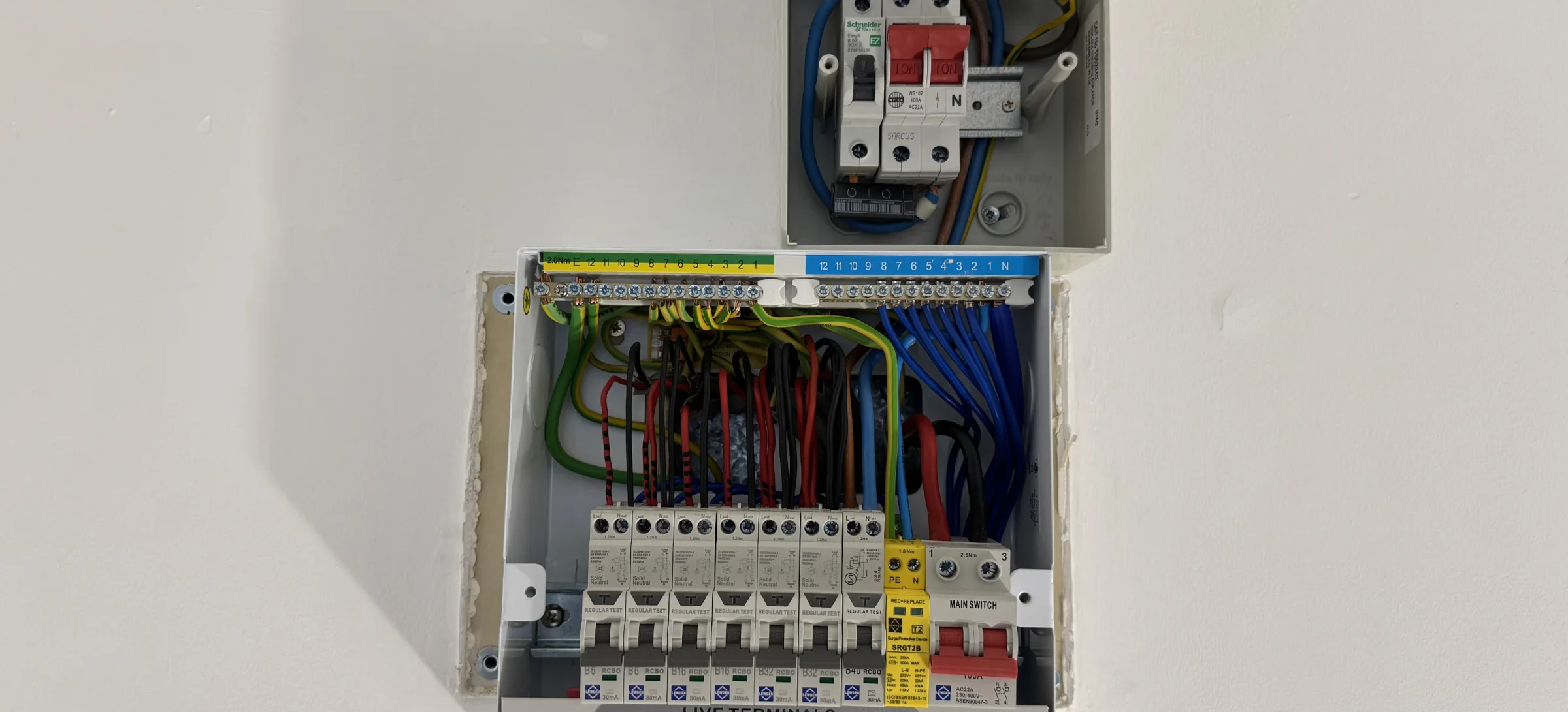 Replacement consumer unit installed in the wall beneath the existing sub‑supply isolator with organised cable terminations, neutral and earth bars and protective devices fitted — c